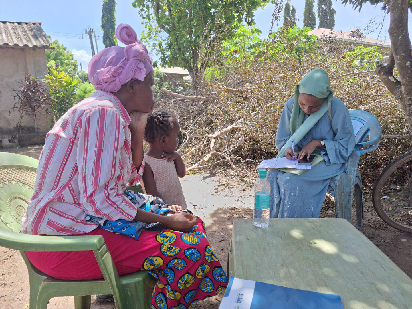 A parent observes their child's assessment process while a field monitor (in blue) reviews the sampling documents and oversees the administration of PAL-ELANA in Lamu, Kenya.